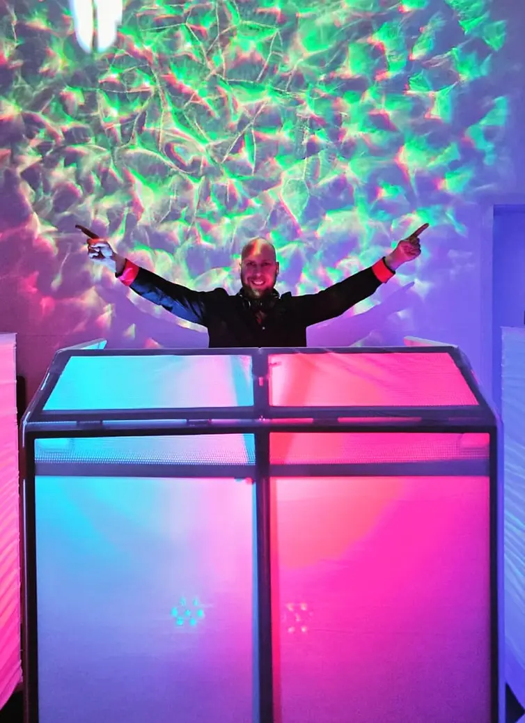 DJ PartyMax zeigt lachend auf die Kamera, während er an seiner Booth performt – Platzhalterbild